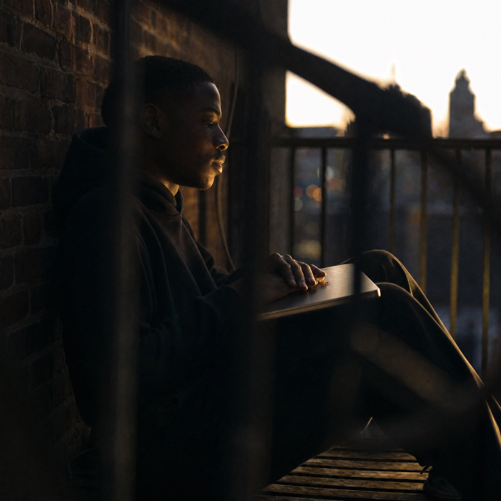 Developer on a fire escape at golden hour, notebook in hand